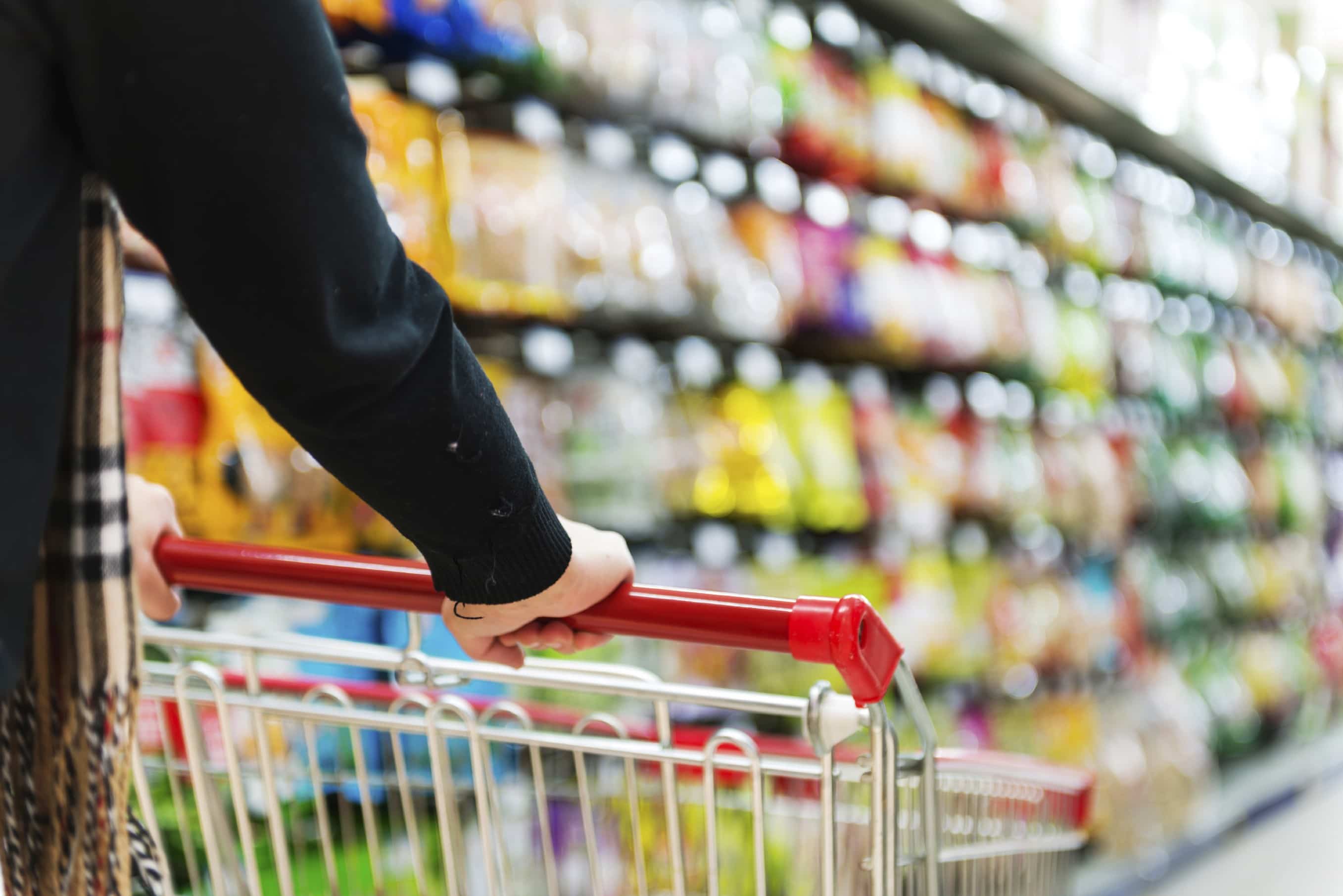 Lady pushing a shopping cart in the supermarket.