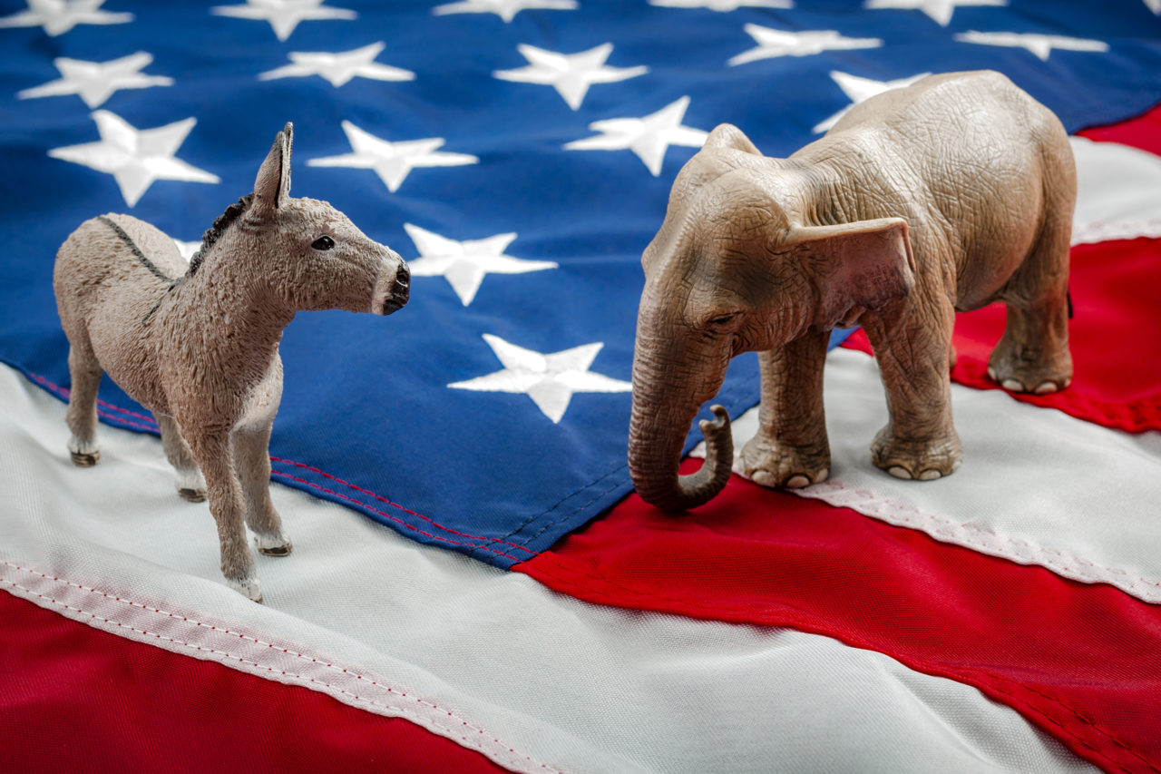 Democrats vs republicans are facing off in a ideological duel on the american flag. In American politics US parties are represented by either the democrat donkey or republican elephant