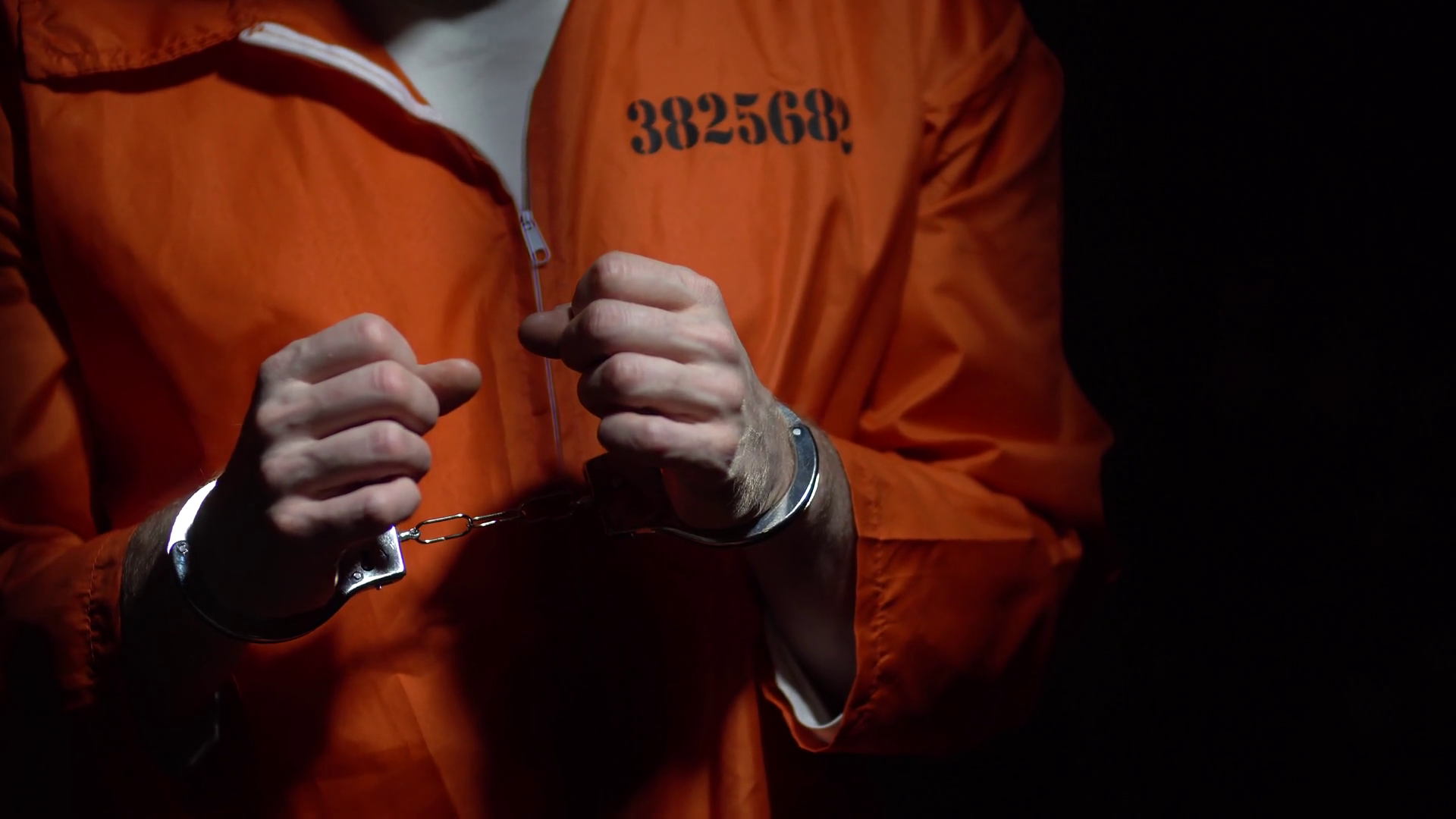 videoblocks-prison-convict-in-handcuffs-dark-at-night-in-cell-behind-bars-sad-depressing-alone-solitary-confinement-male-adult-prisoner-wearing-orange-jumpsuit-young-offender-serving-time-tr