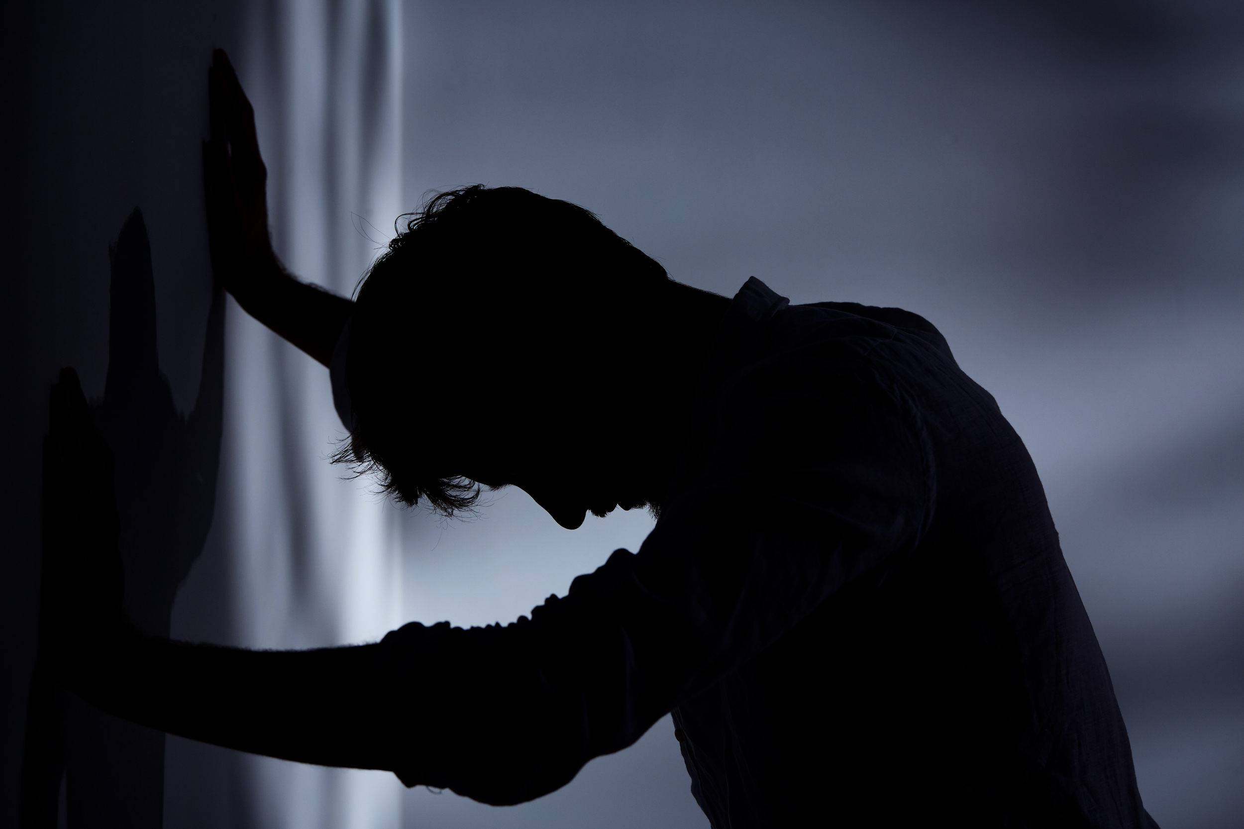 Man leaning hands against wall