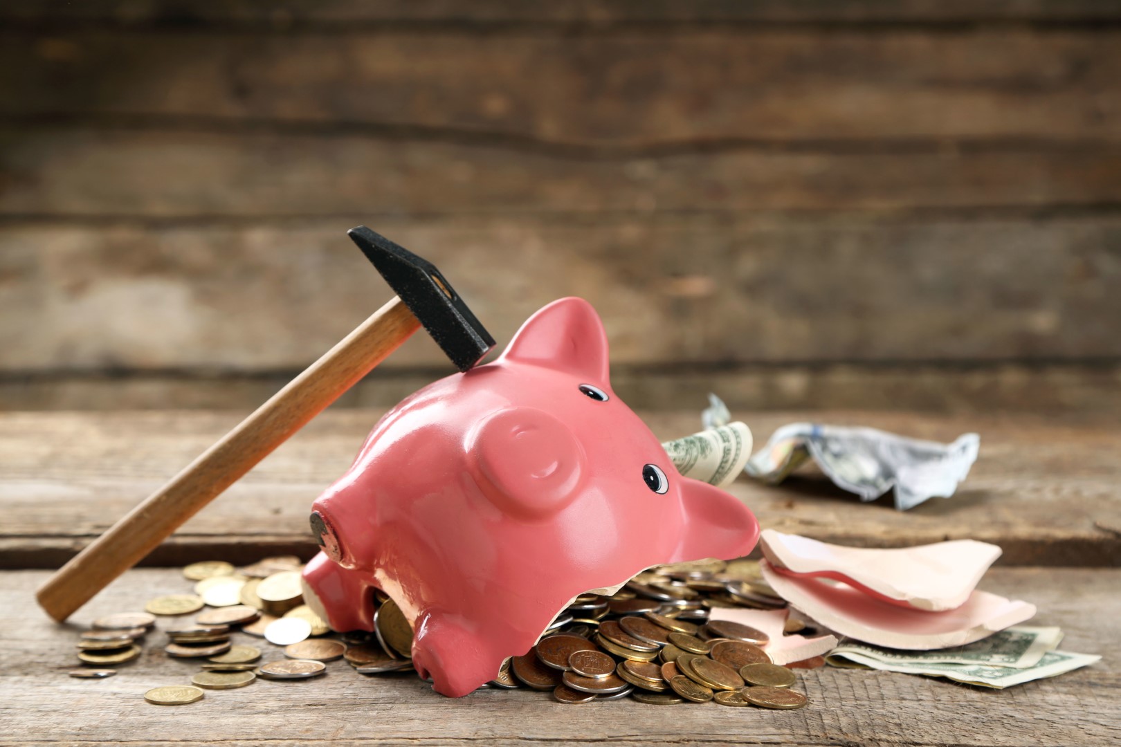 Broken piggy bank with cash and coins on wooden background