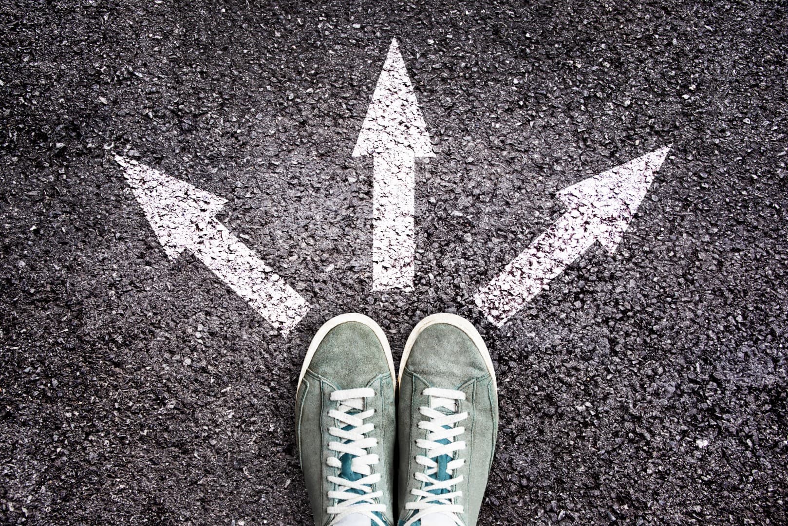 Shoes and arrows pointing in different directions on asphalt floor