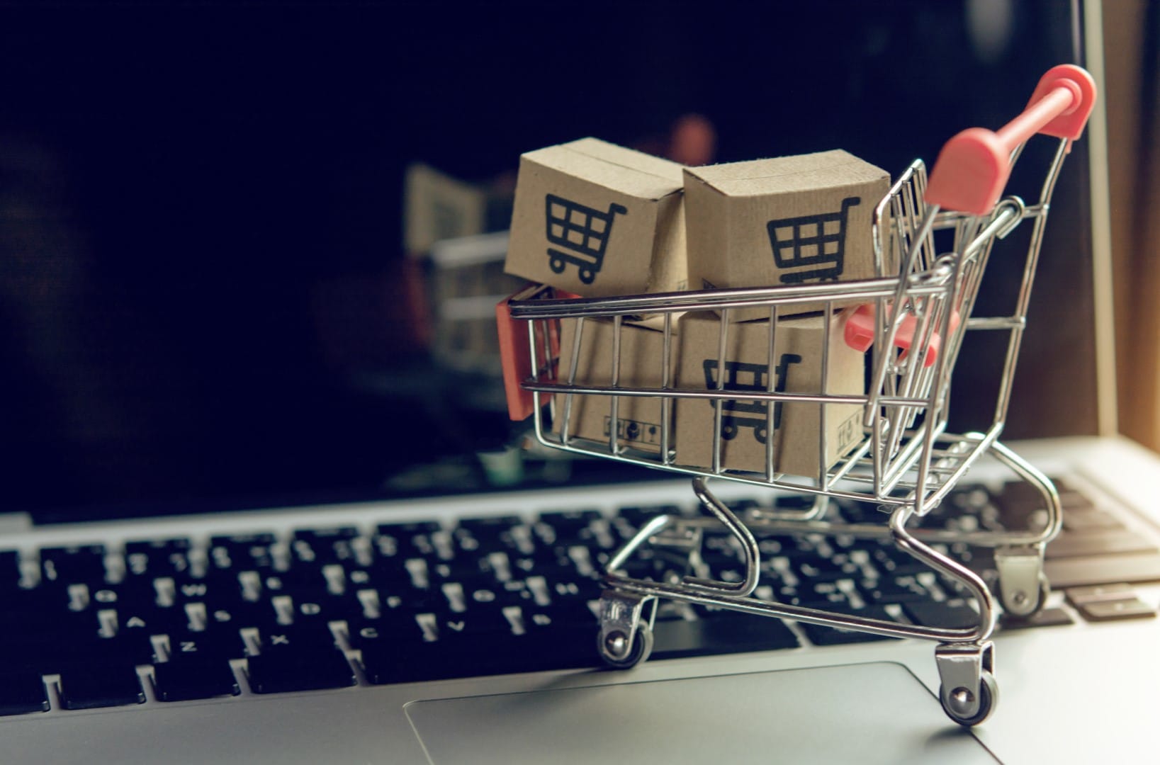 Shopping online concept - Parcel or Paper cartons with a shopping cart logo in a trolley on a laptop keyboard. Shopping service on The online web. offers home delivery..