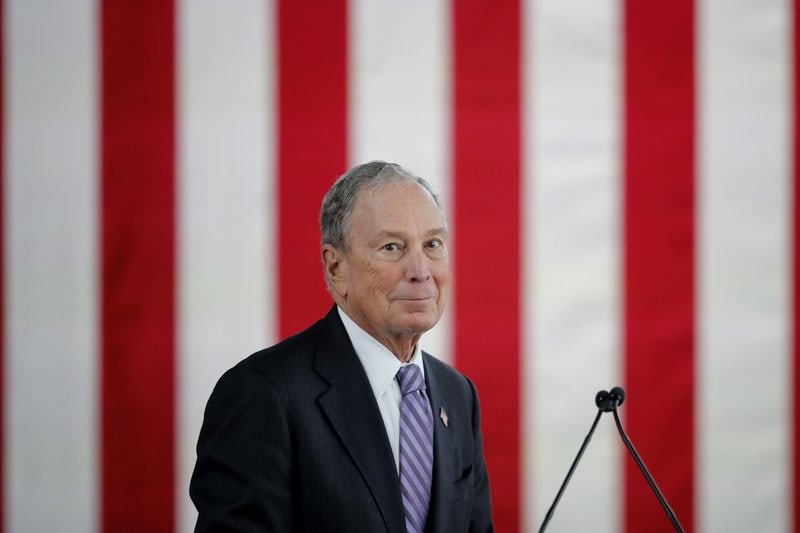 bloomberg, mike - in front of a red flag