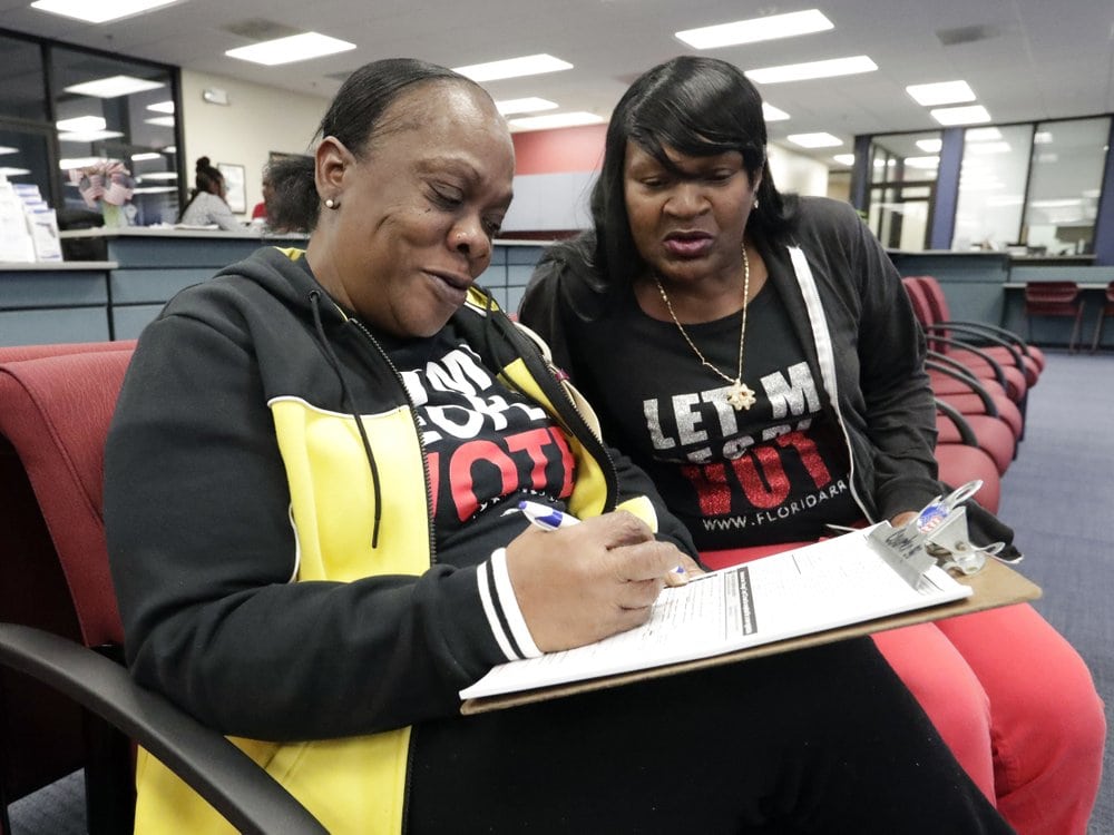 FILE - In this Jan. 8, 2019, file photo, former felon Yolanda Wilcox, left, fills out a voter registration form as her best friend Gale Buswell looks on at the Supervisor of Elections office in Orlando, Fla. In a ruling Thursday, Tuesday, March 31, 2020, the 11th U.S. Circuit Court of Appeals declined to hear an appeal from Florida Gov. Ron DeSantis to limit the reach on Amendment 4, the ballot measure approved overwhelmingly by voters in 2018 that allowed felons to regain the right to vote. (AP Photo/John Raoux, File)