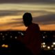 FILE - In this March 25, 2020, file photo, a person looks at a phone as the sun sets, in Kansas City, Mo. The city along with neighboring counties is under Stay at Home orders to help prevent the spread of COVID-19, the disease caused by the new coronavirus. (AP Photo/Charlie Riedel, File)