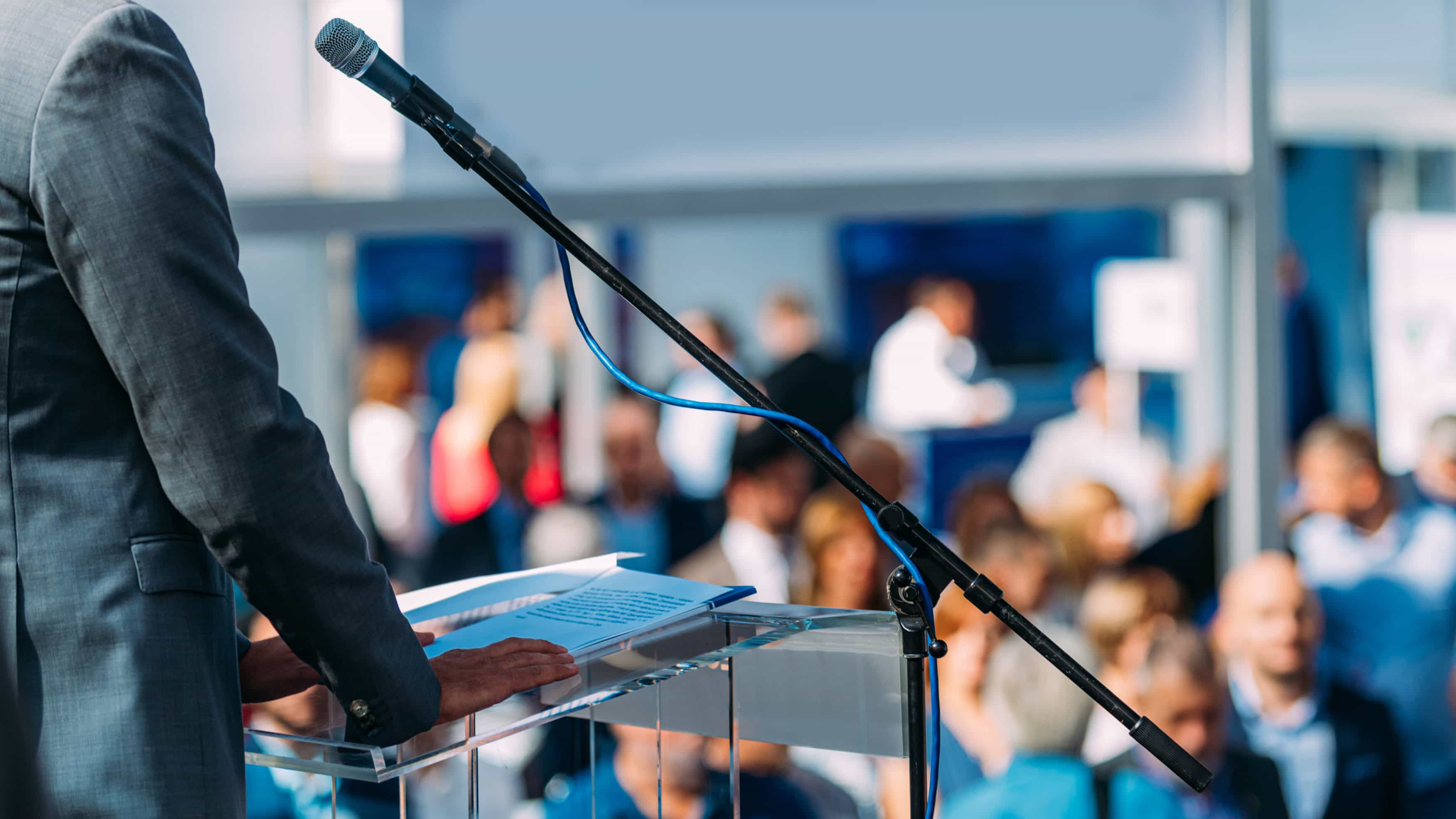 Male Speaker Standing In Front Of Microphones