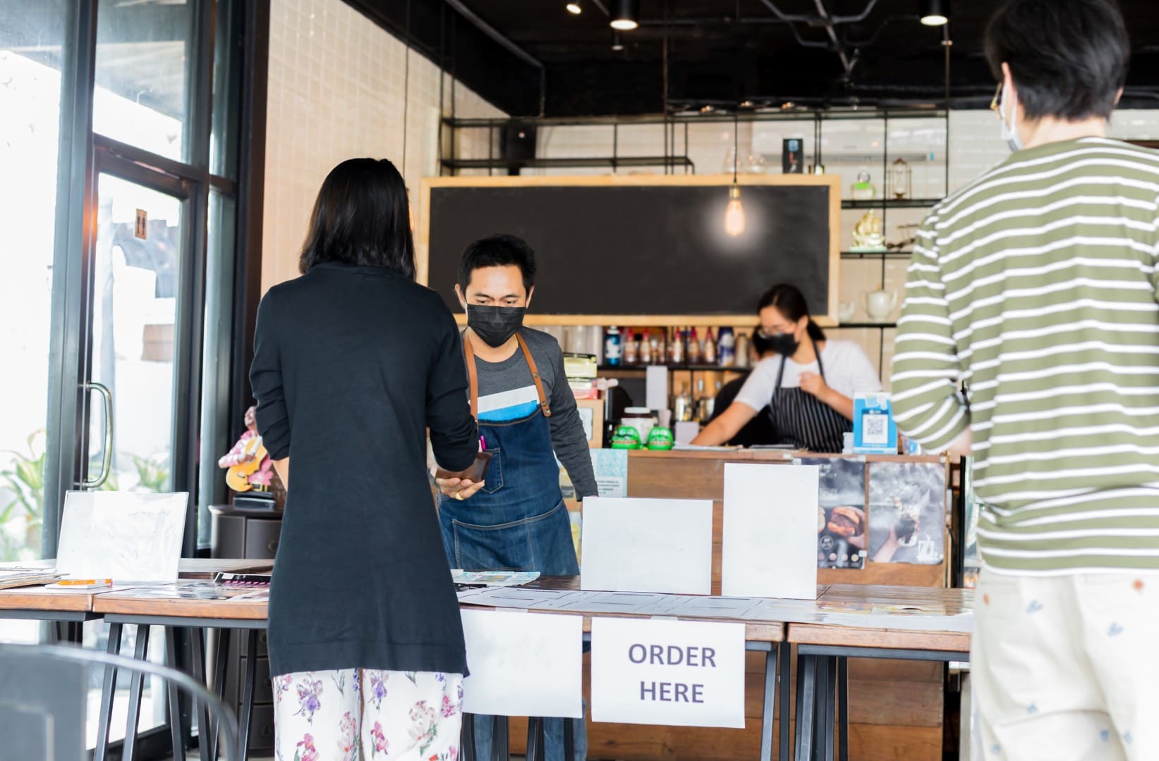 Social distance conceptual small business waiter serving customer at coffee shop.