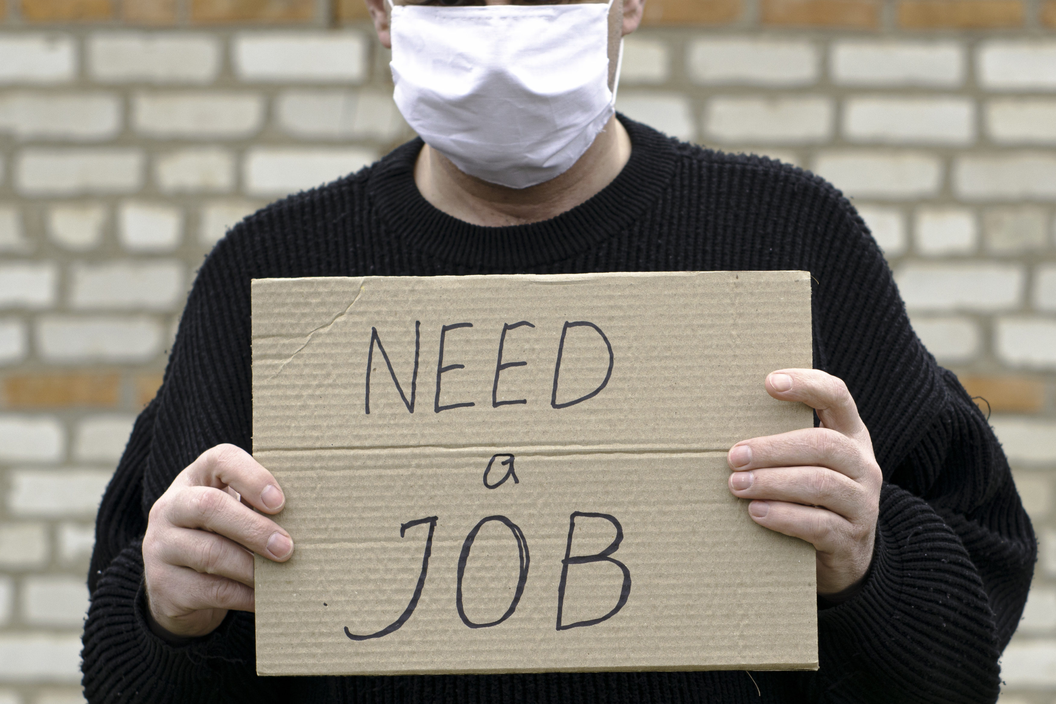 concept unemployment and coronavirus a man in a medical hygienic mask is holding a cardboard tablet with a inscription need a job