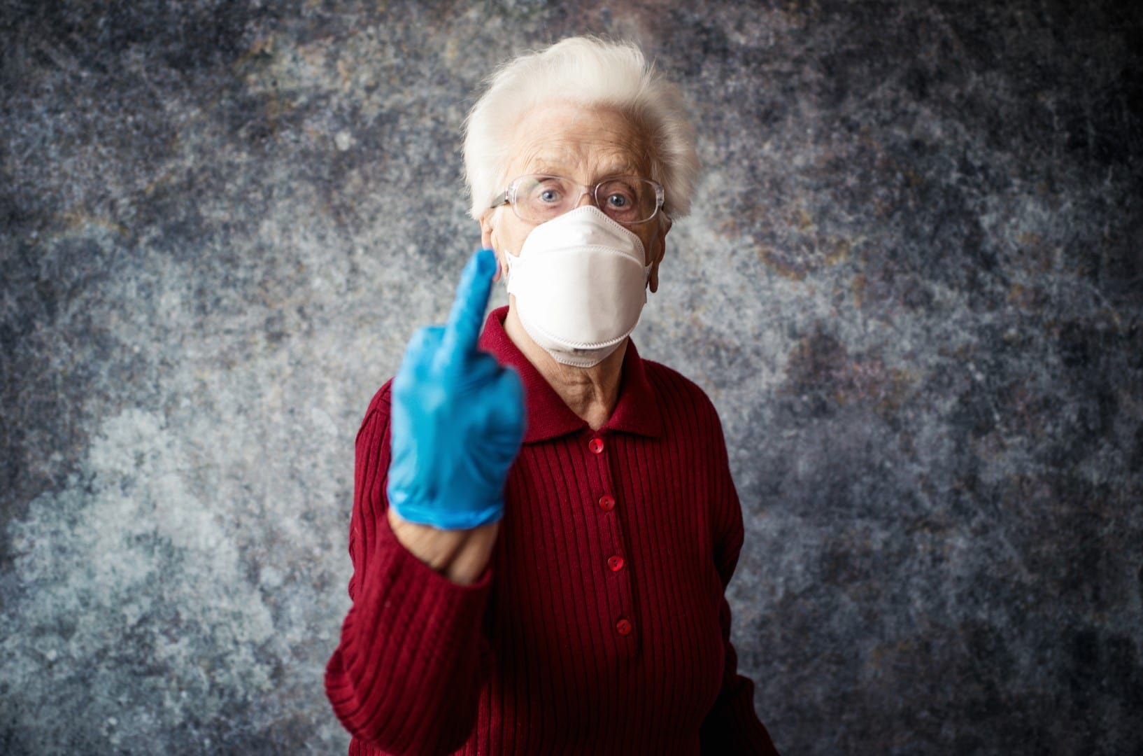 Old grandmother protect herself from coronavirus infection with medical gloves and respirator mask