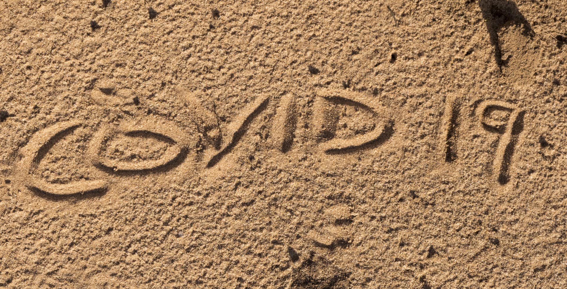 Covid 19 name written in sand
