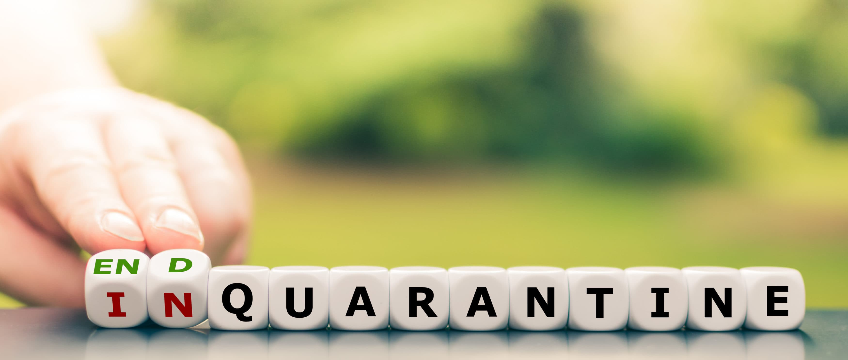 Hand turns dice and changes the expression "in quarantine" to "end quarantine".