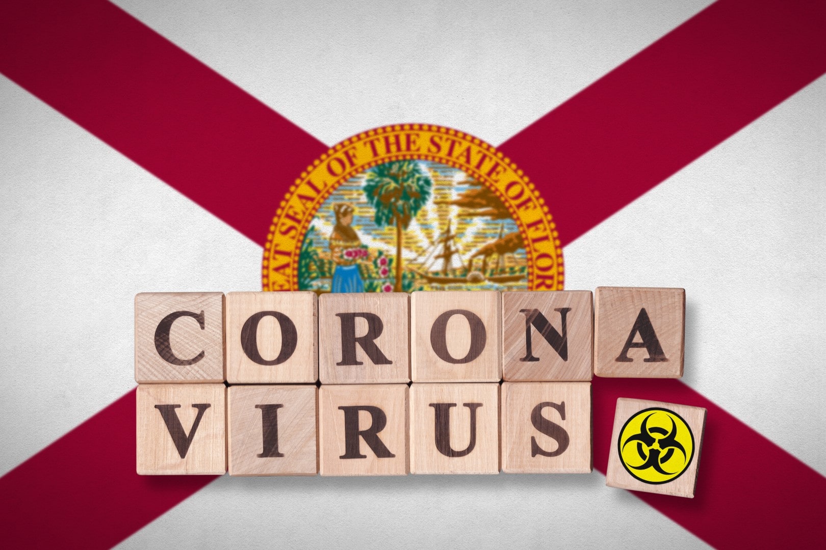 The state of Florida flag and wooden blocks with letters spelling CORONAVIRUS and quarantine symbol on it. Novel Coronavirus (2019-nCoV) concept for an outbreak occurs in Florida, US.