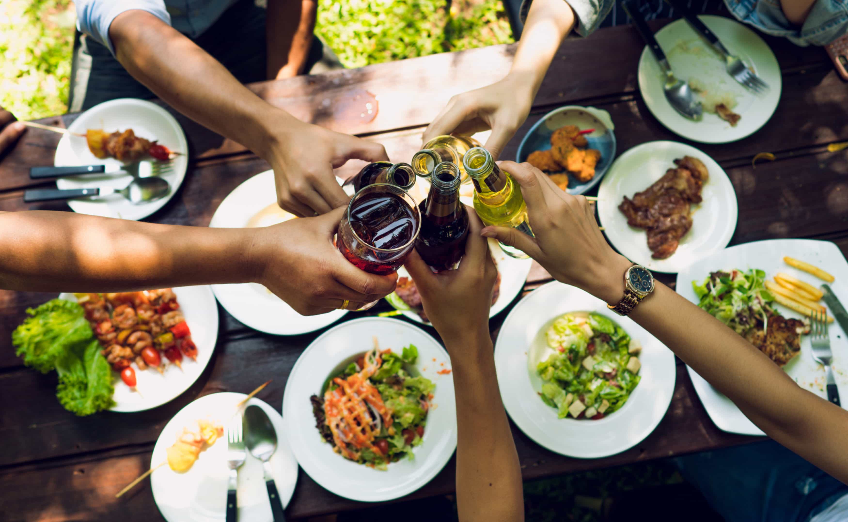 People are eating on vacation. They eat outside the house and clink beer house.