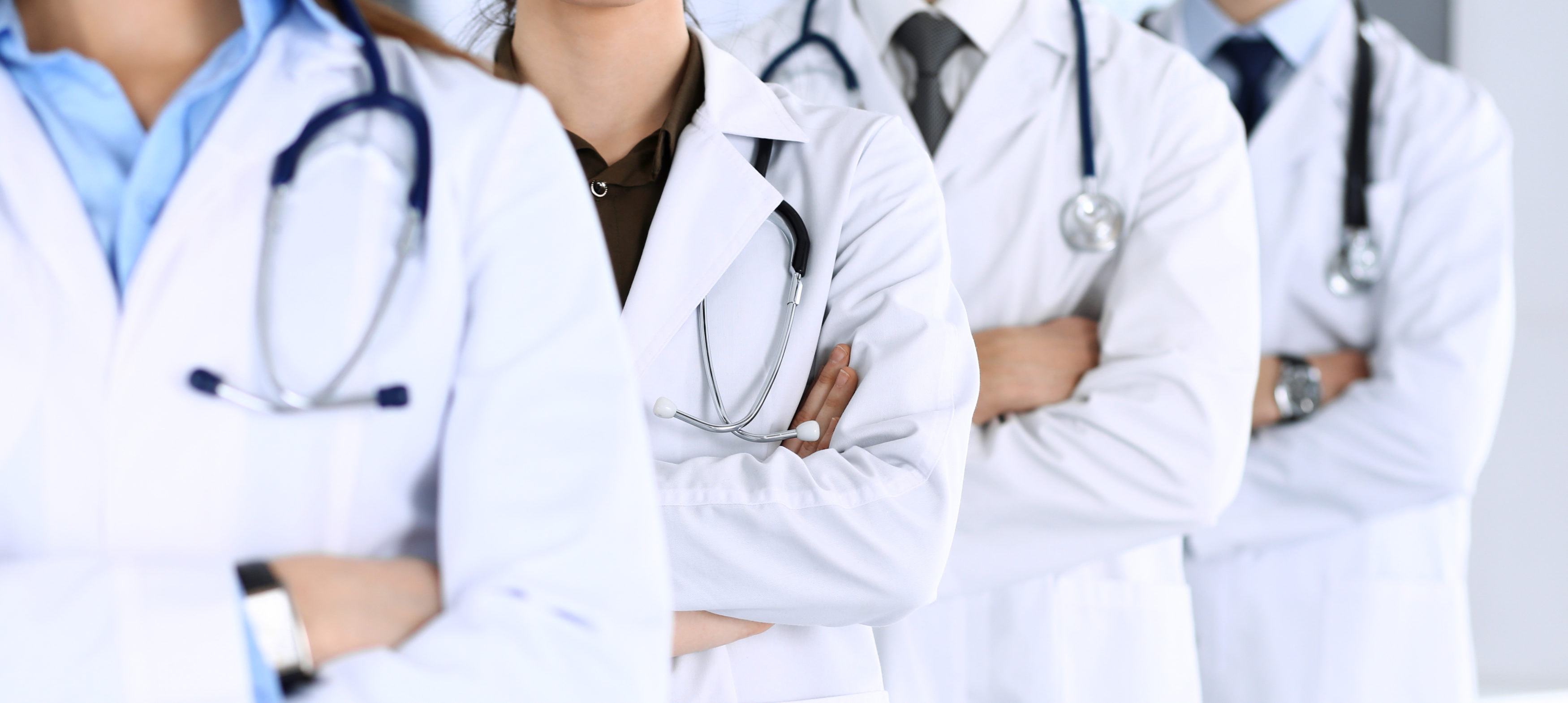 Group of modern doctors standing as a team with arms crossed in hospital office. Physicians ready to examine and help patients. Medical help, insurance in health care, best desease treatment and medicine concept