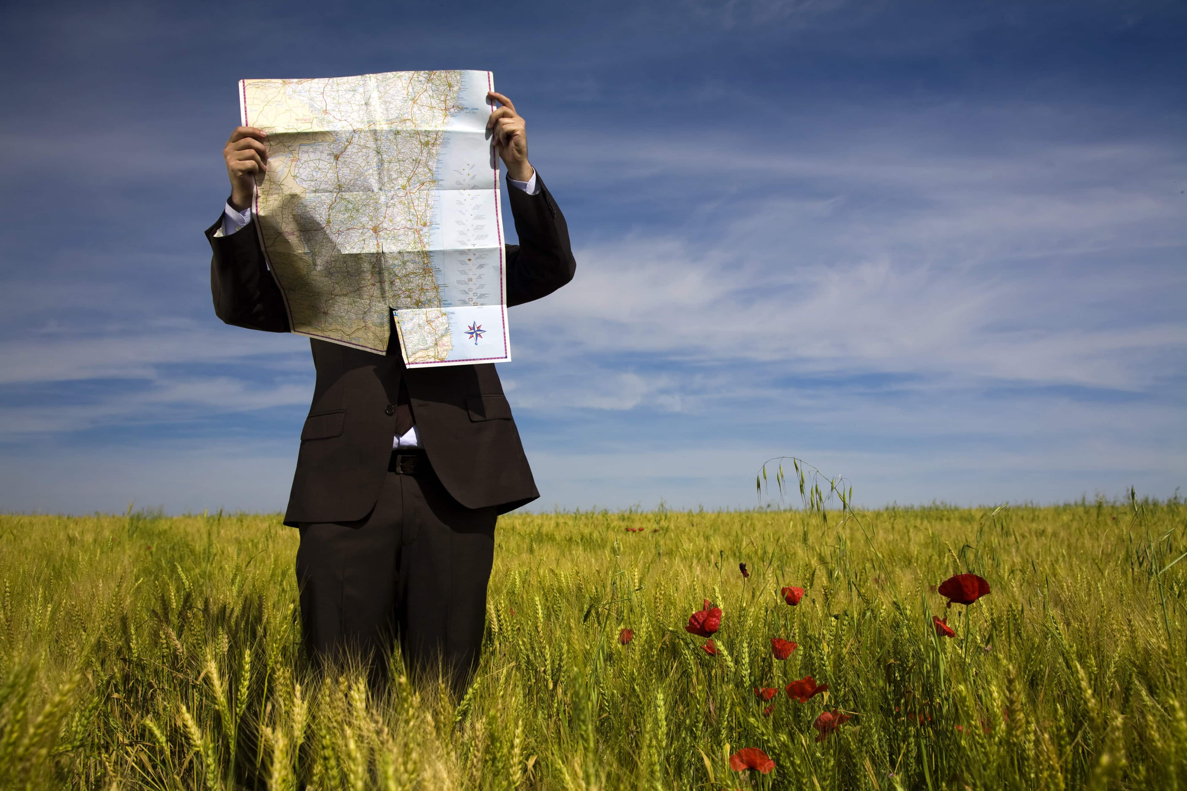 businessman lost in field using a map