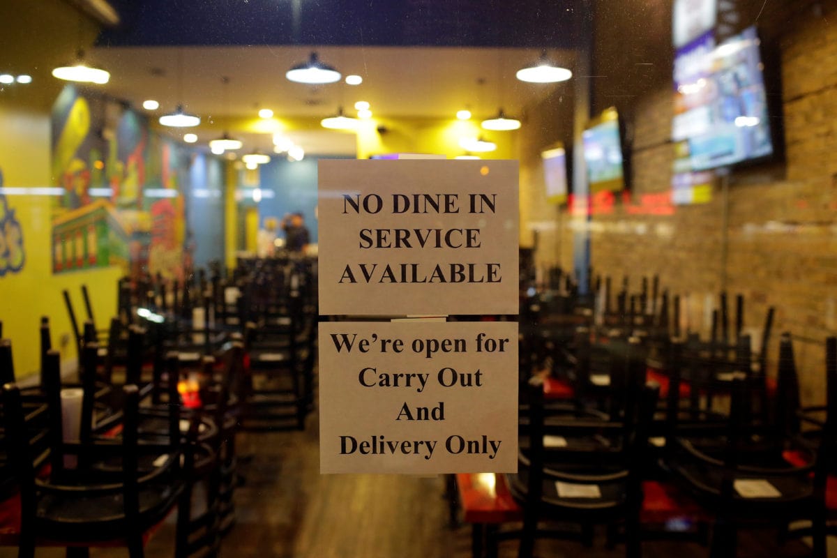 Signs are displayed on the window of a restaurant to inform customers that the dinning area is closed in Chicago