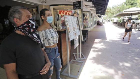 Restaurant workers Alvyn Lopez, left, and Maria Lindo watch for customers as they stand outside Aura at Books & Books, Monday, July 6, 2020, on Miami Beach, Florida's famed Lincoln Road. In Miami-Dade County, population 2.7 million, Mayor Carlos Gimenez ordered the closing of restaurants and certain other indoor places, including vacation rentals, seven weeks after they were allowed to reopen. Beaches will reopen on Tuesday after being closed over the weekend. (AP Photo/Wilfredo Lee)
