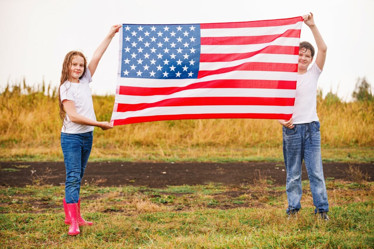 Happy little girl and boy  in a white t-shirt, with American flag.