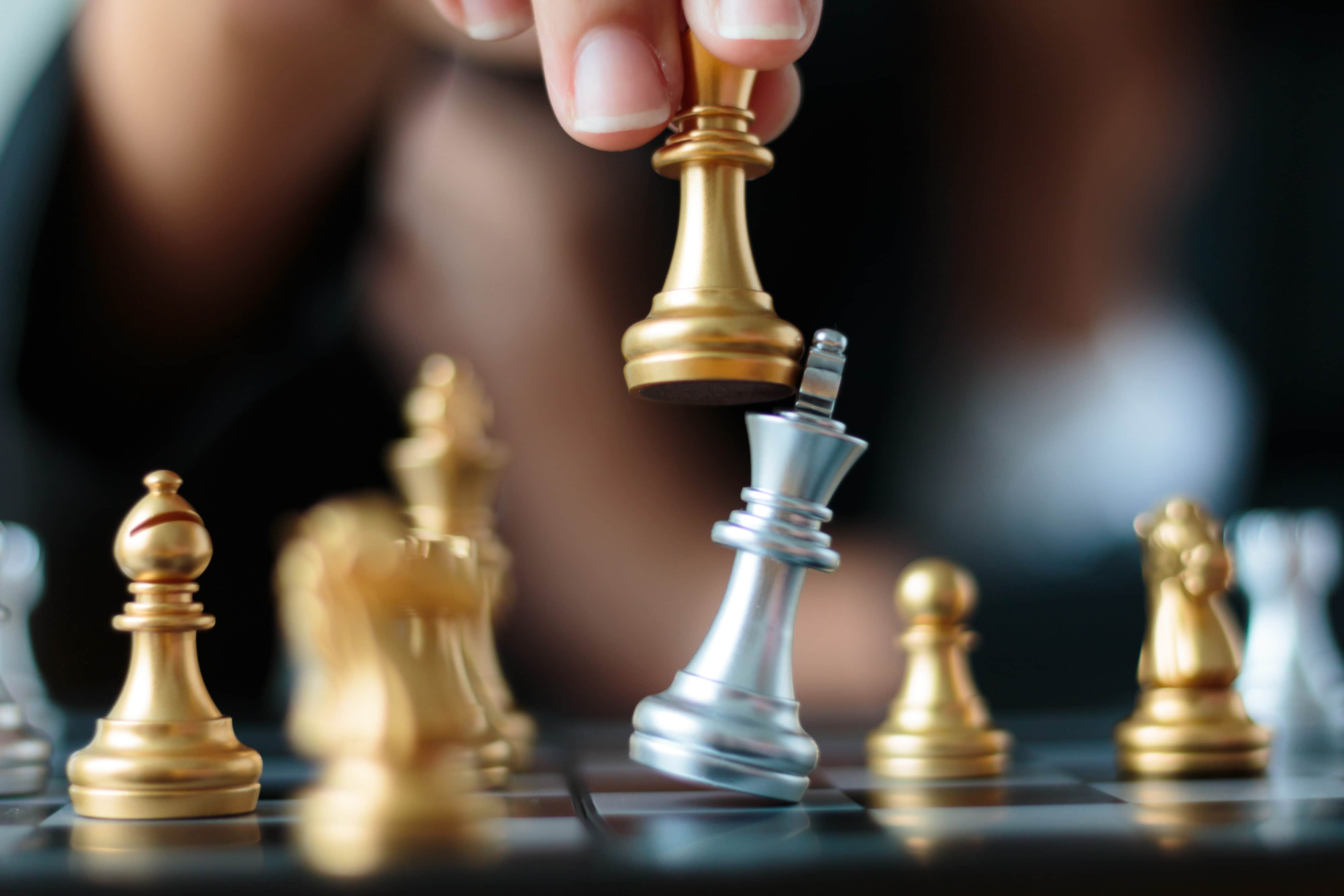 Close up shot hand of business woman moving golden chess to defeat and kill silver king chess on white and black chess board for business challenge competition winner and loser concept