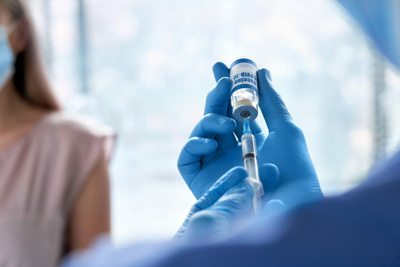 Male doctor holding syringe taking coronavirus vaccine for patient vaccination.