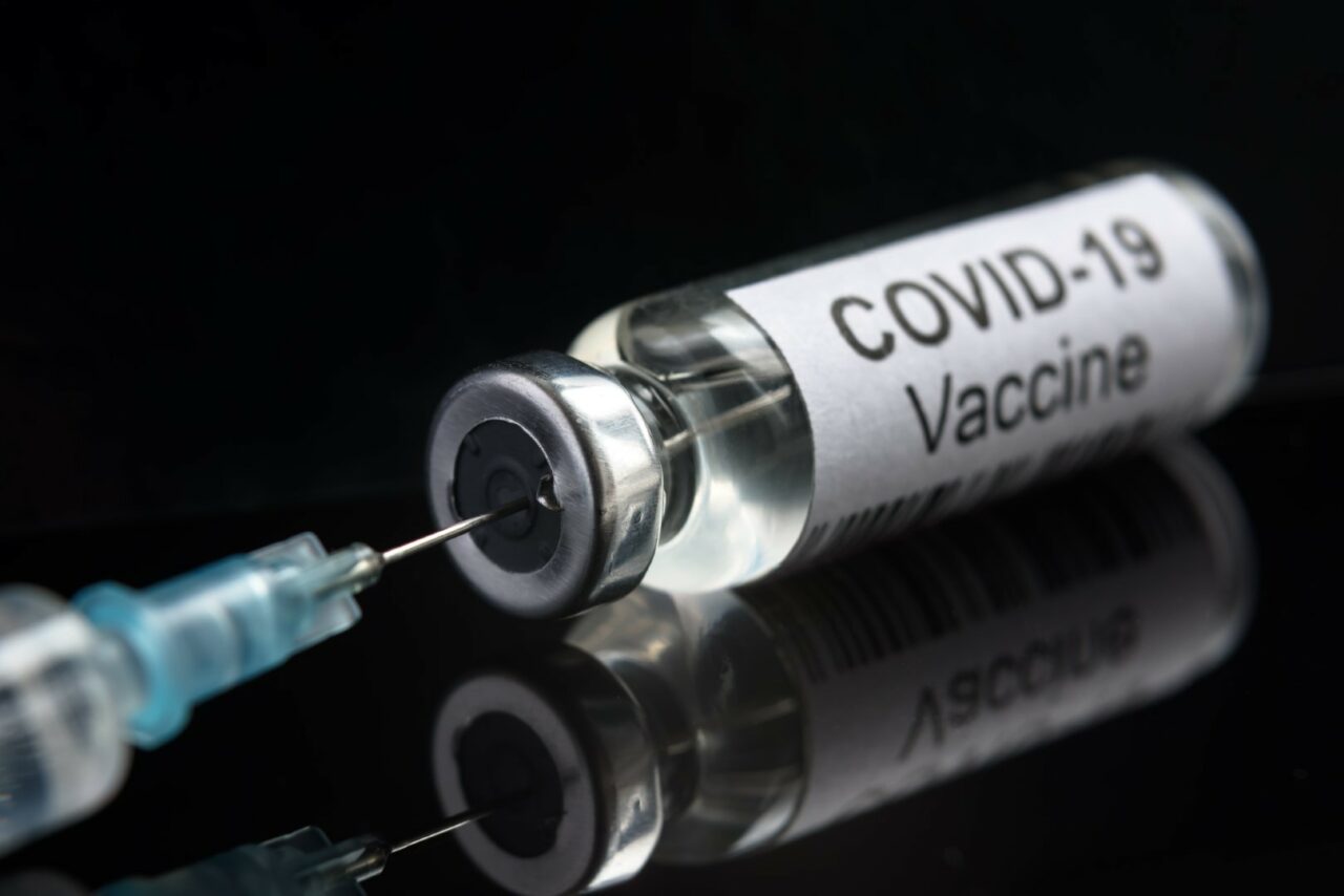 COVID-19 coronavirus vaccine on black, syringe and bottle close-up