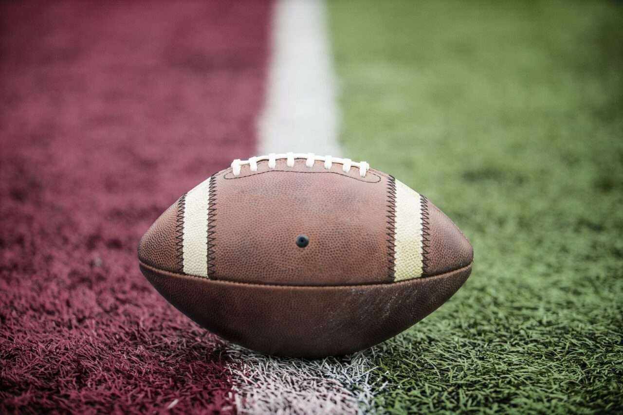 Closeup of an American Football resting on the goal line at a football stadium. Looks like its a touchdown.