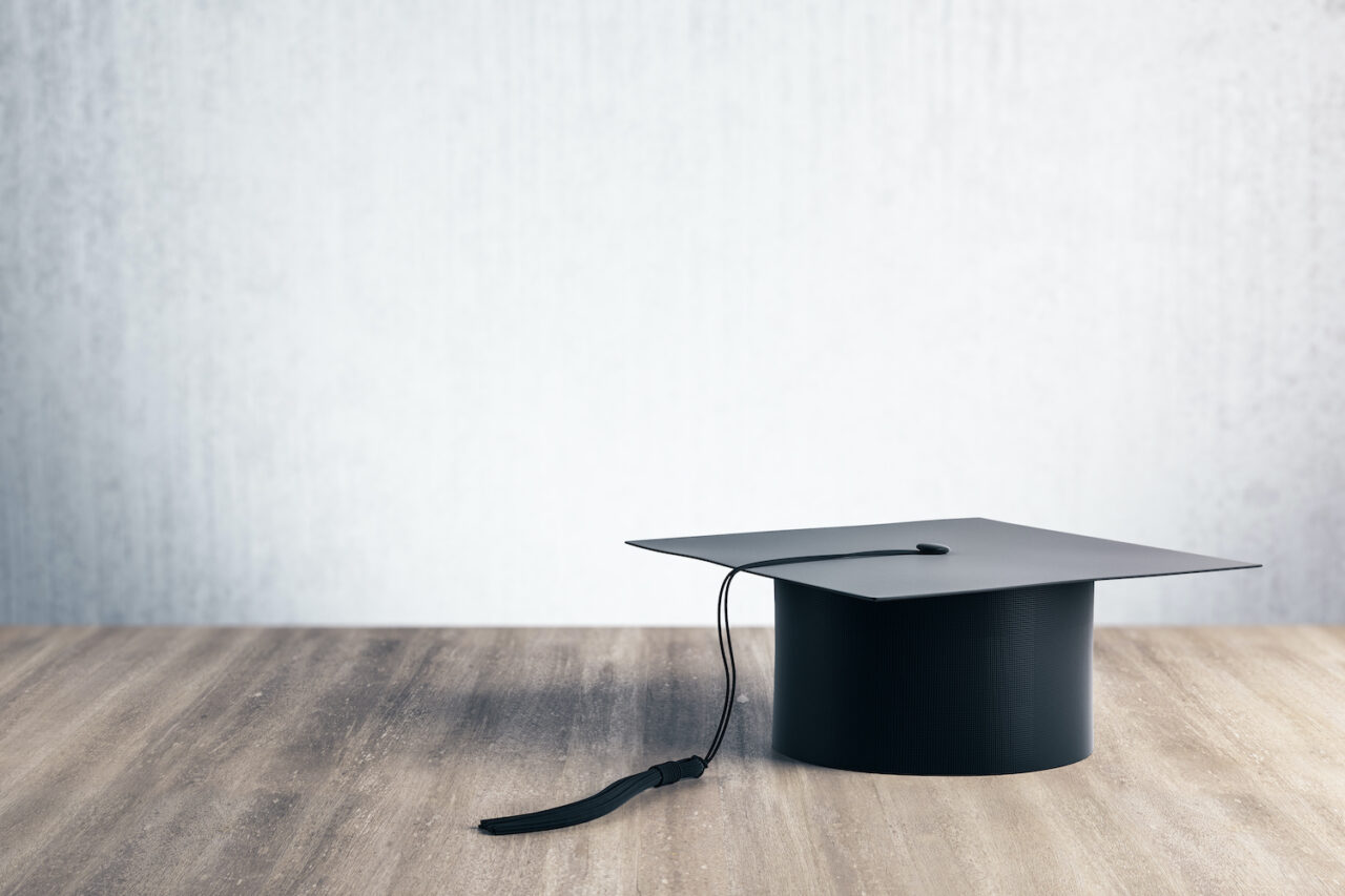 Black graduation cap on wooden table.