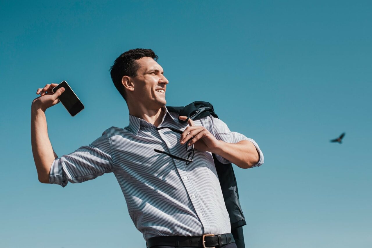 Office worker throwing his smartphone away while having a rest