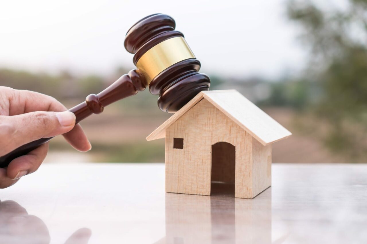 Judge gavel and house model property auction for real estate law concept. Lawyer hand holding gavel wooden knocking home ownership for buying selling or foreclosure on nature background.