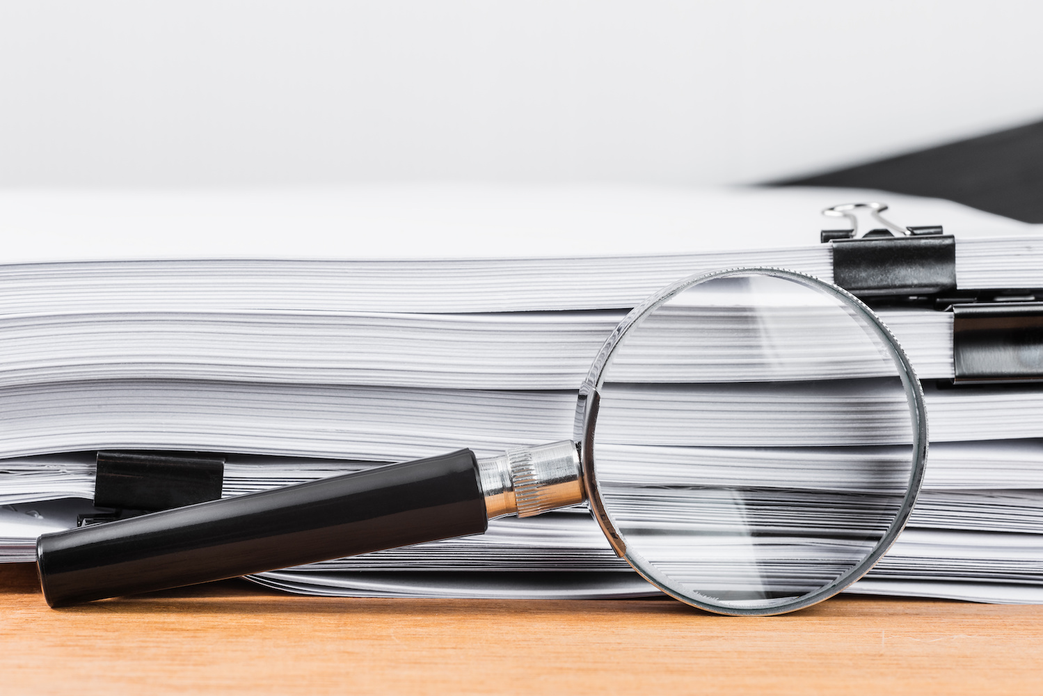 Close-up magnifying glass place on wooden table and search to edge of white documents