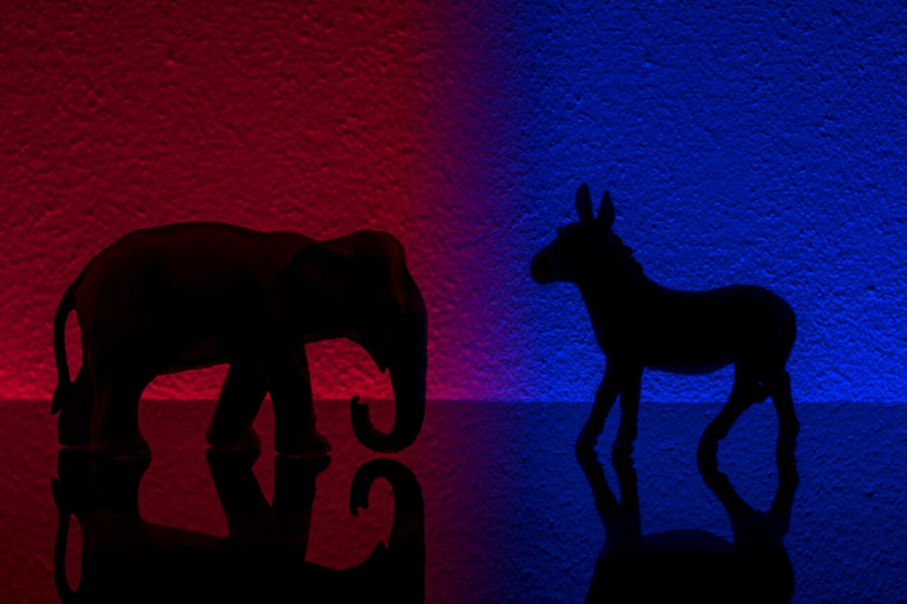 Democrats vs republicans are facing off in a ideological duel on blue and red backgrounds. In American politics US parties are represented by either the democrat donkey or republican elephant