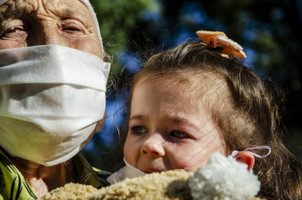 An old grandmother and a small child wearing a medical mask during the coronavirus pandemic. Children and old people are waiting for vaccination against coronavirus infection.