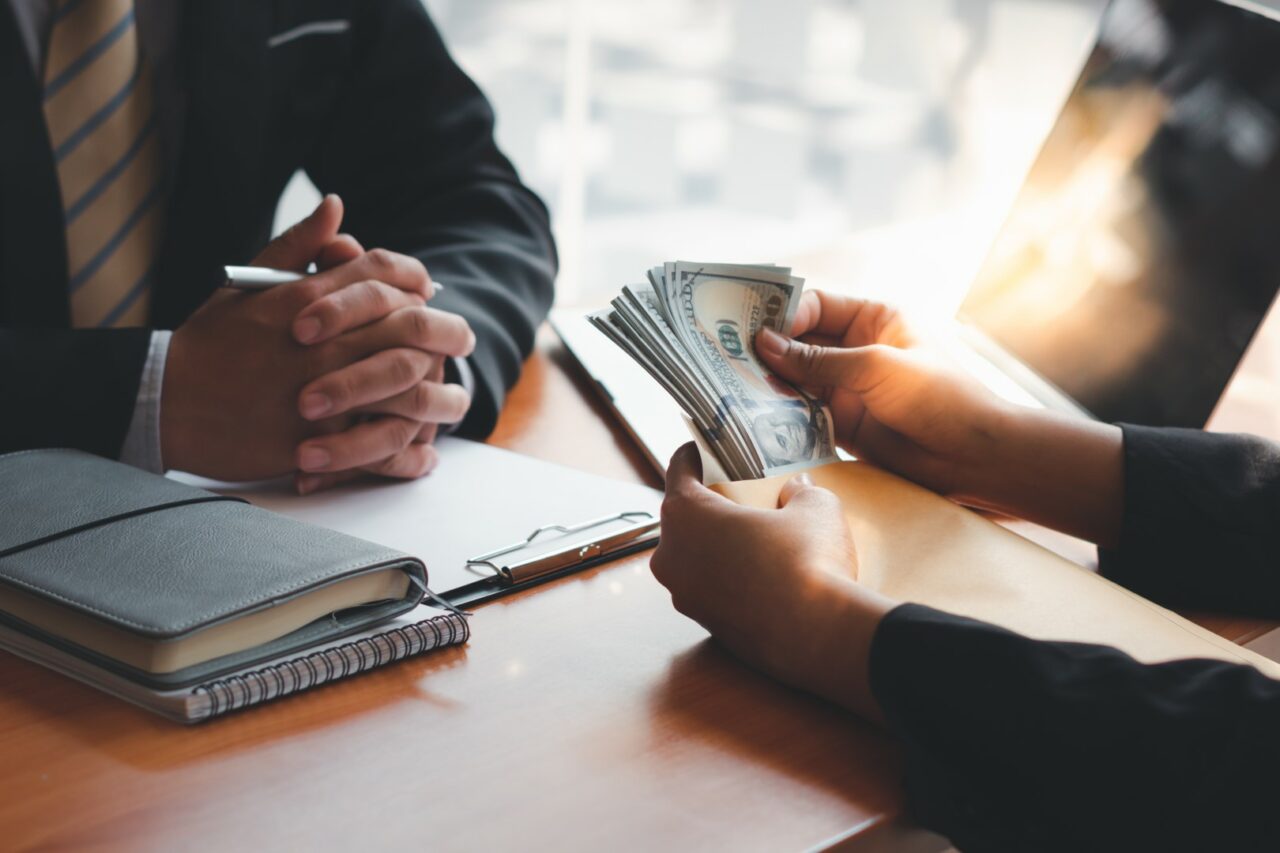 Man offering batch of hundred dollar bills. Venality, bribe, corruption concept. Hand giving money - United States Dollars (or USD). Hand receiving money from businessman.