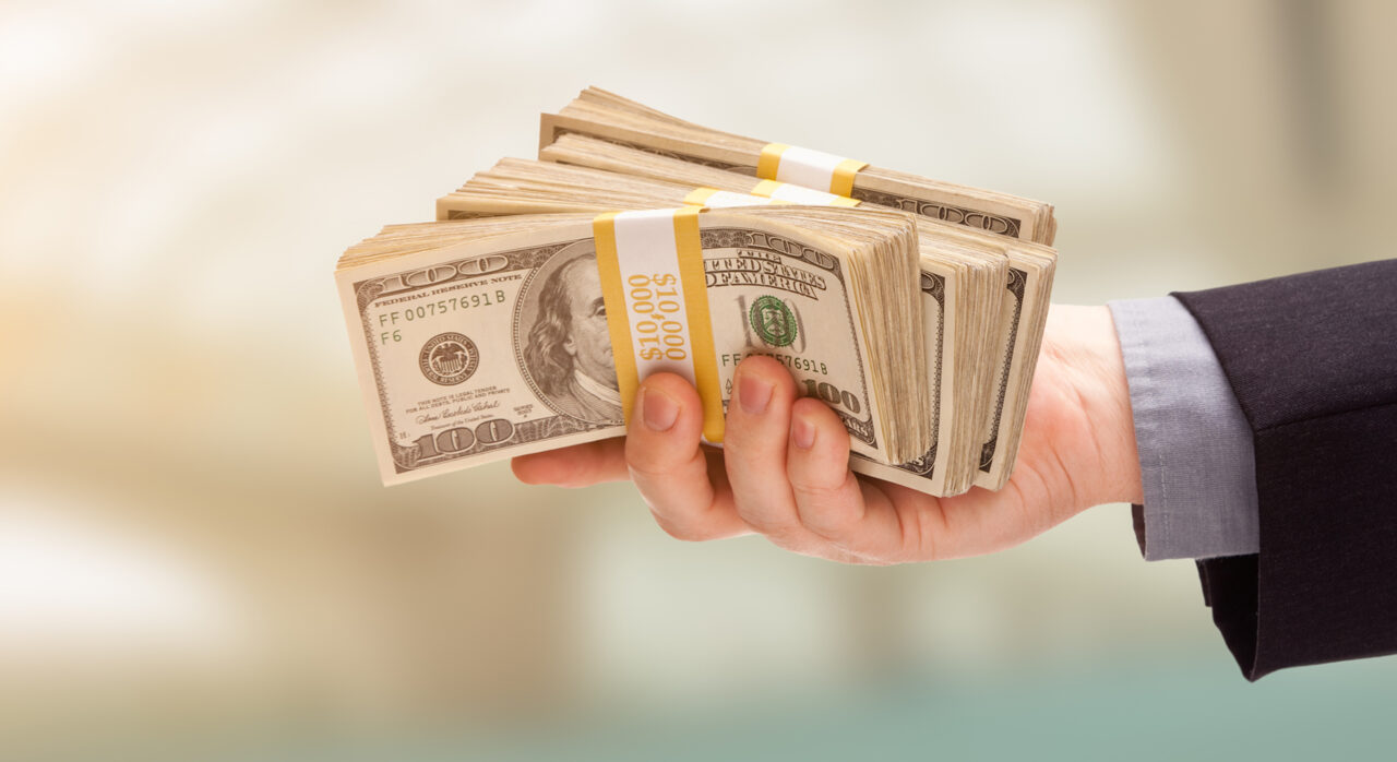 Male Hand Holding Stack of Cash Wide Banner With Room For Copy.