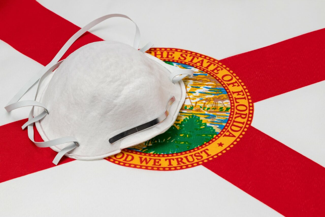 Florida state flag and N95 face mask. Concept of state and local government face covering mandate, order, requirement and social distancing during Covid-19 coronavirus pandemic