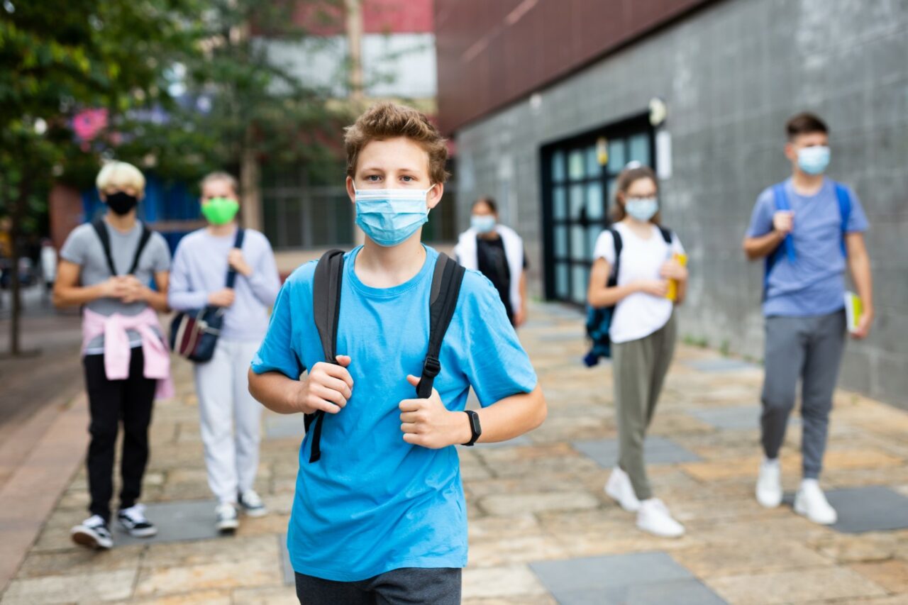 Teenager in protective mask going to school in autumn