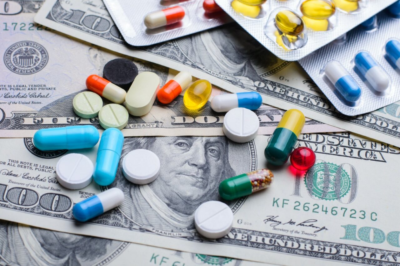 Different colorful pills capsules on money bills. Concept of expensive treatment, medicine, medical insurance.