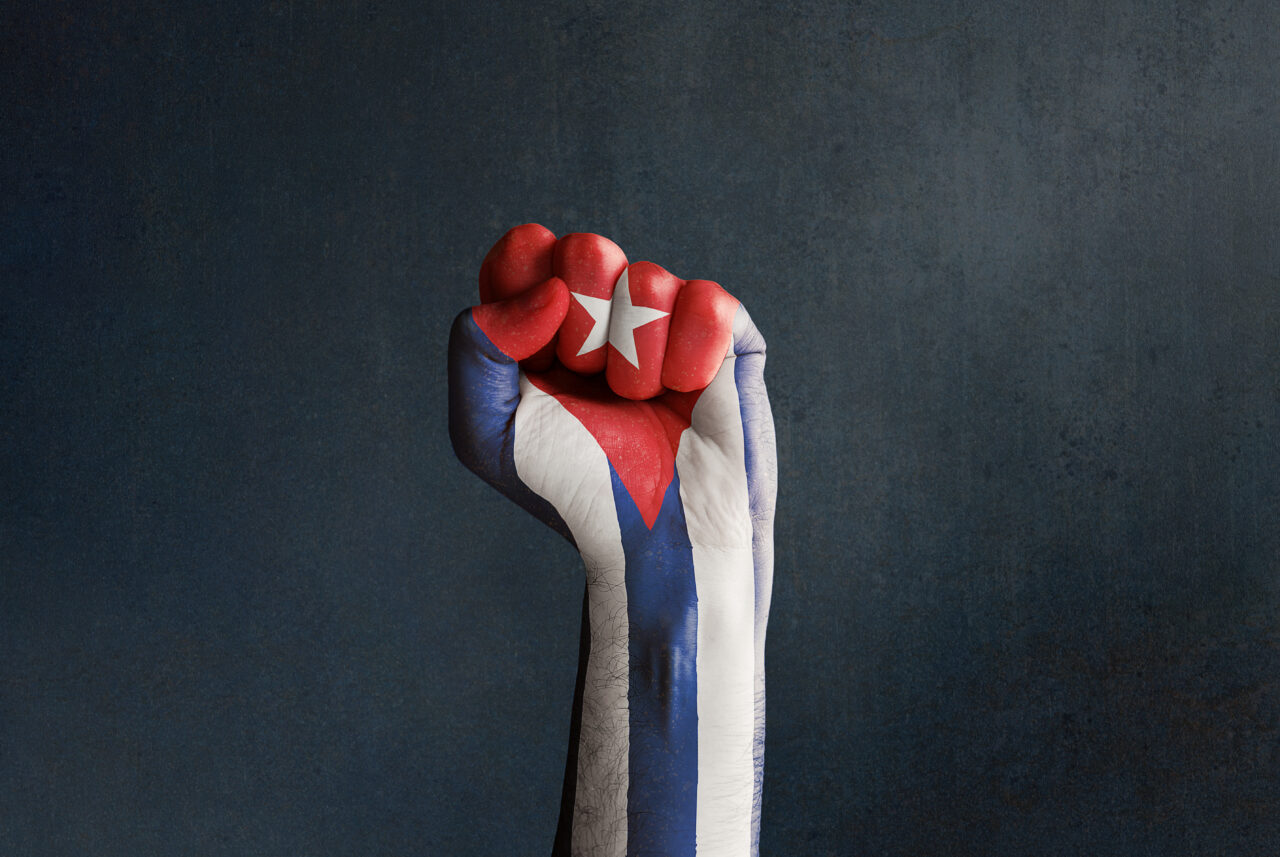 Stock photo of a raised fist with Cuban flag on a dark backgroun