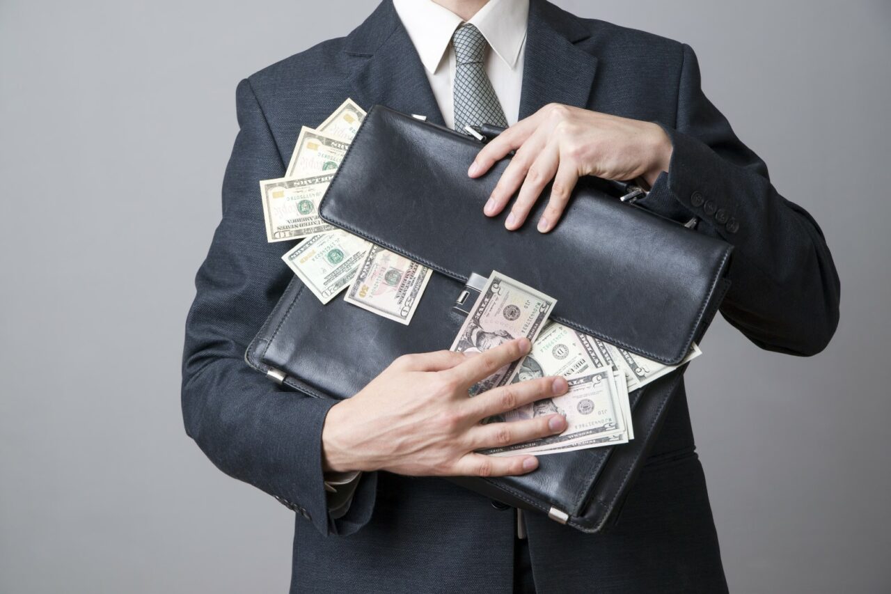 Businessman with a briefcase full of money in the hands of