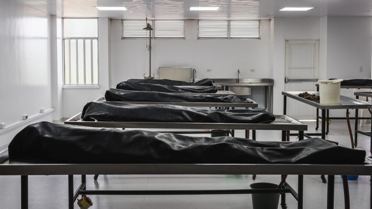 Covered human corpses on tables in a morgue / mortuary waiting f