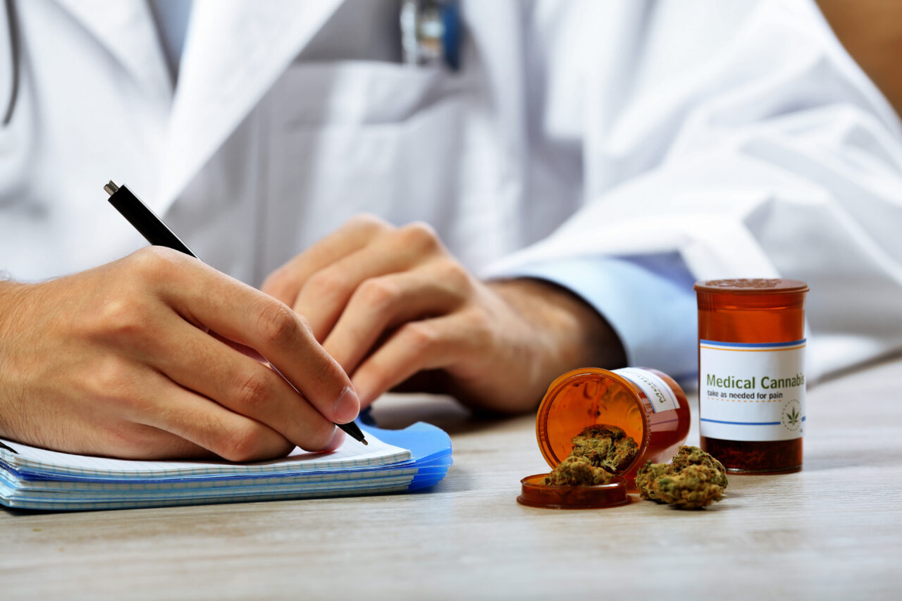 Doctor writing on prescription blank and bottle with medical can