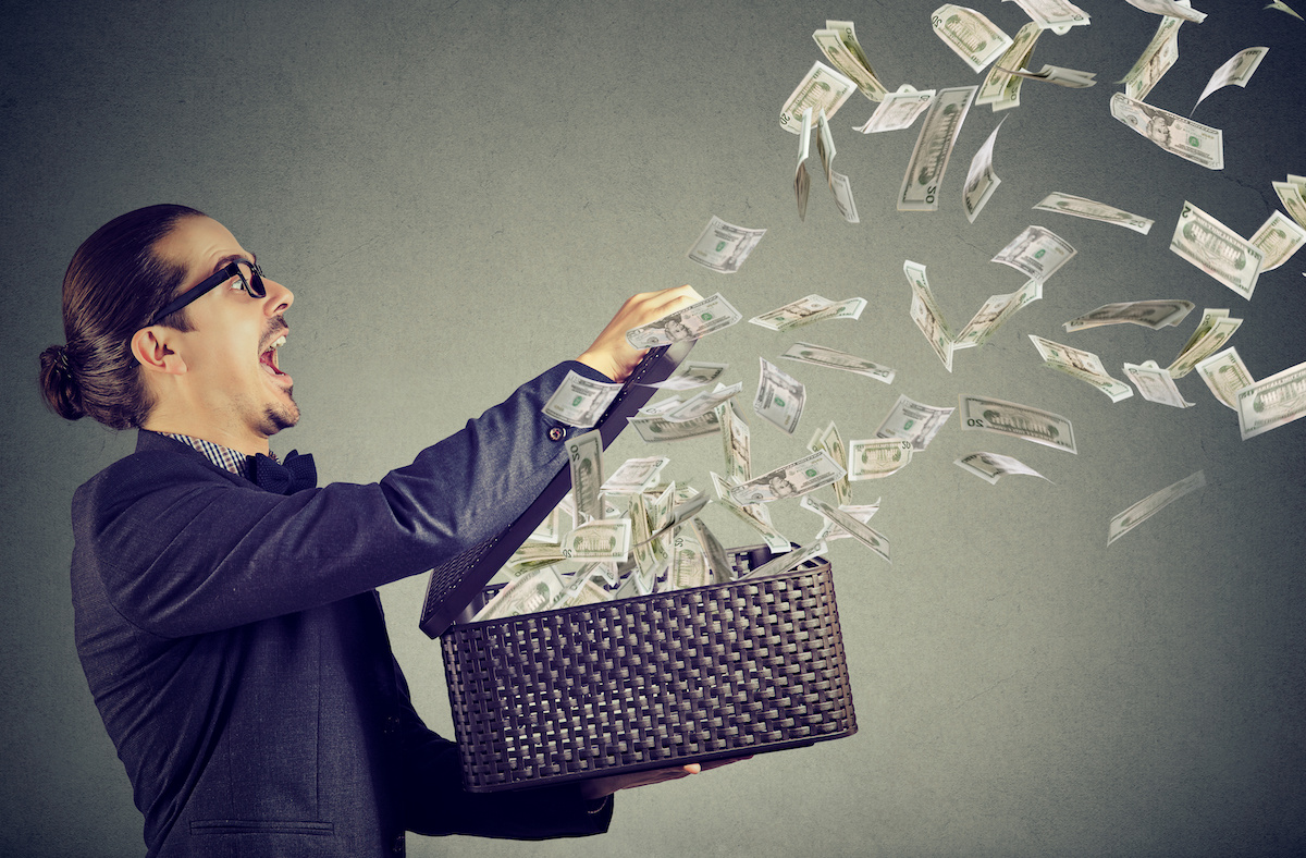 Excited business man opening an box letting dollar banknotes to fly away