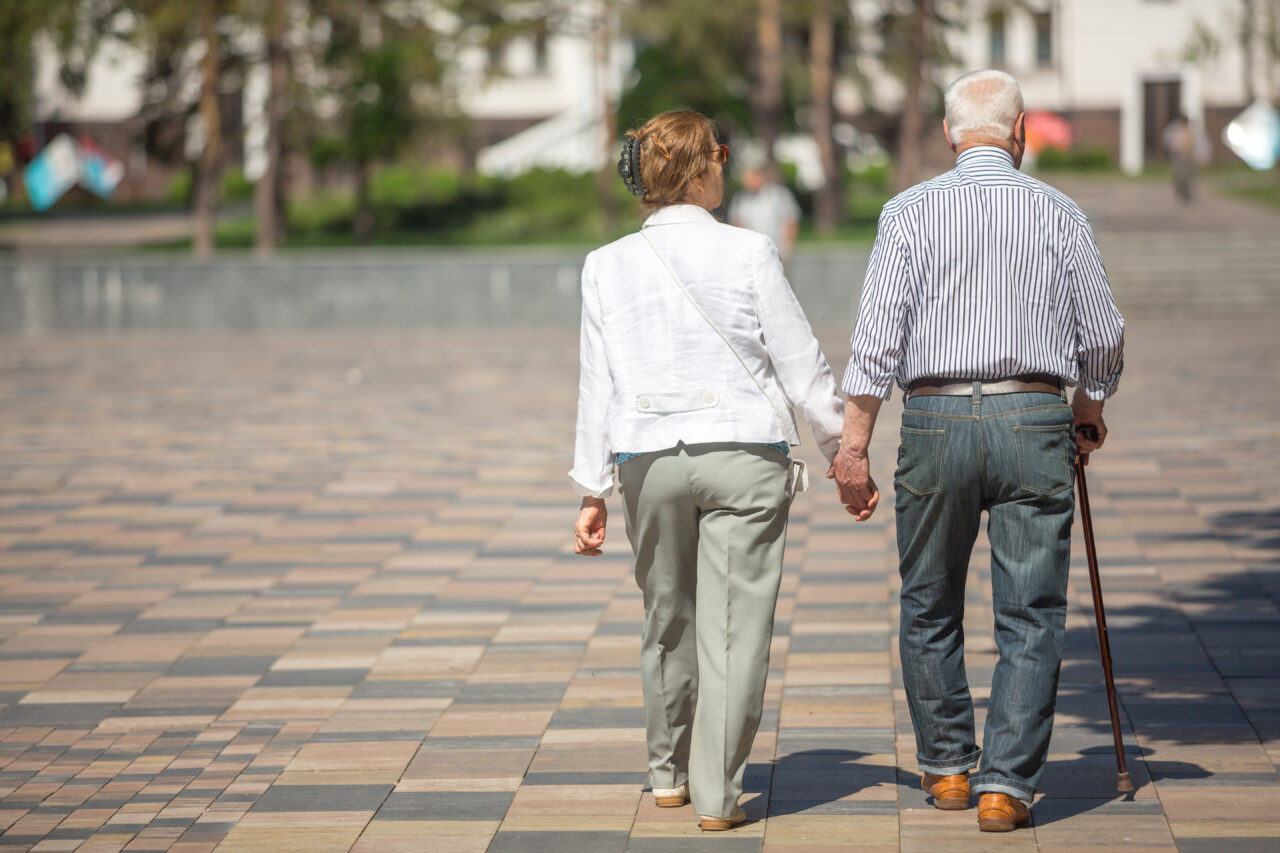 Senior adults walking in a park holding hands