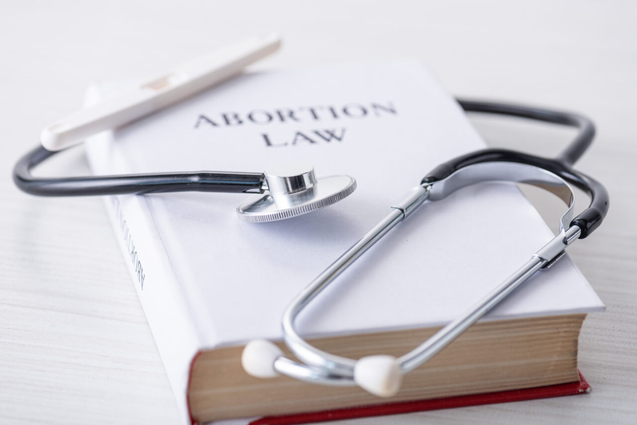 selective focus of stethoscope on book with abortion law lettering near pregnancy test