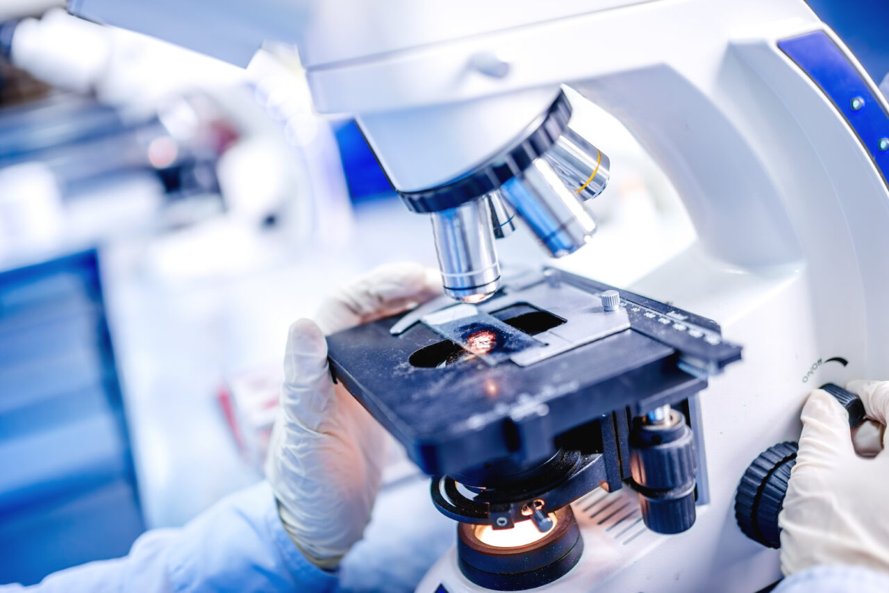 Details of medical laboratory, scientist hands using microscope