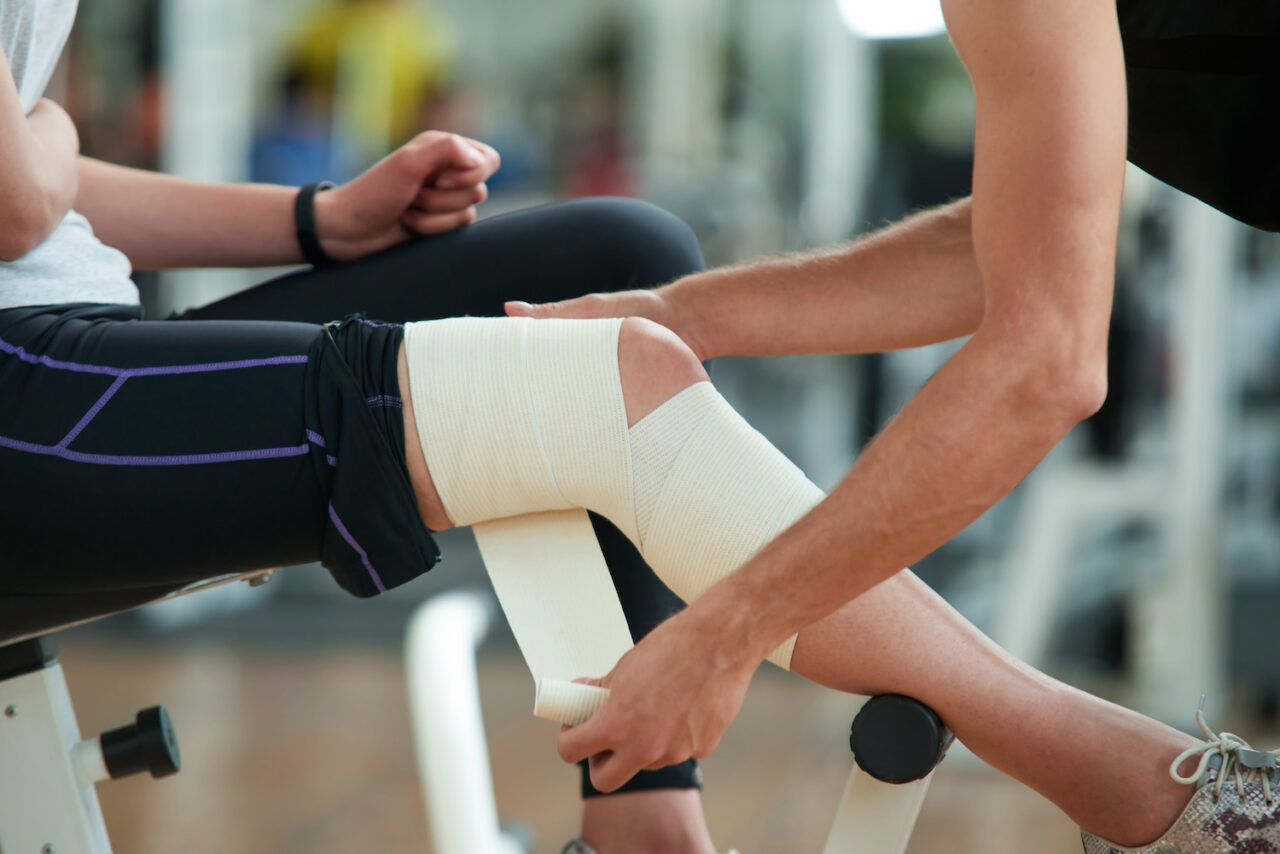 Man wrapping bandage around knee.