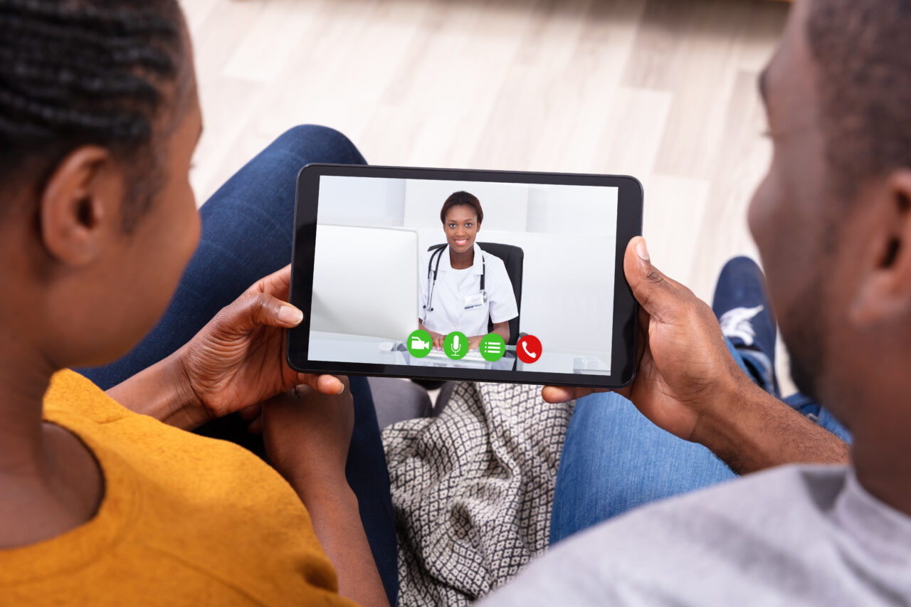 Close-up Of An African Couple Video Conferencing With Happy Fema