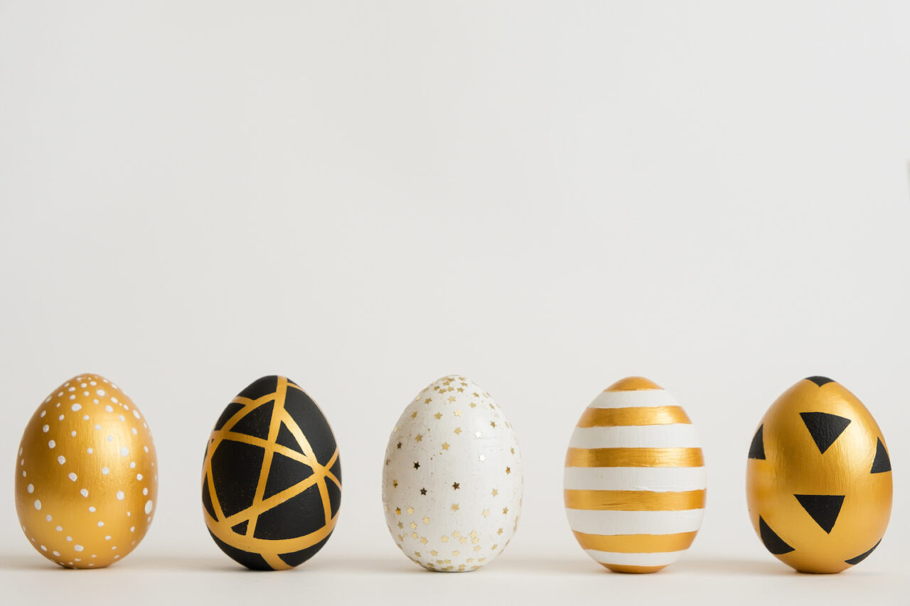 Easter golden decorated eggs stand in a row on white background. Minimal easter concept. Happy Easter card with copy space for text. Top view, flatlay.