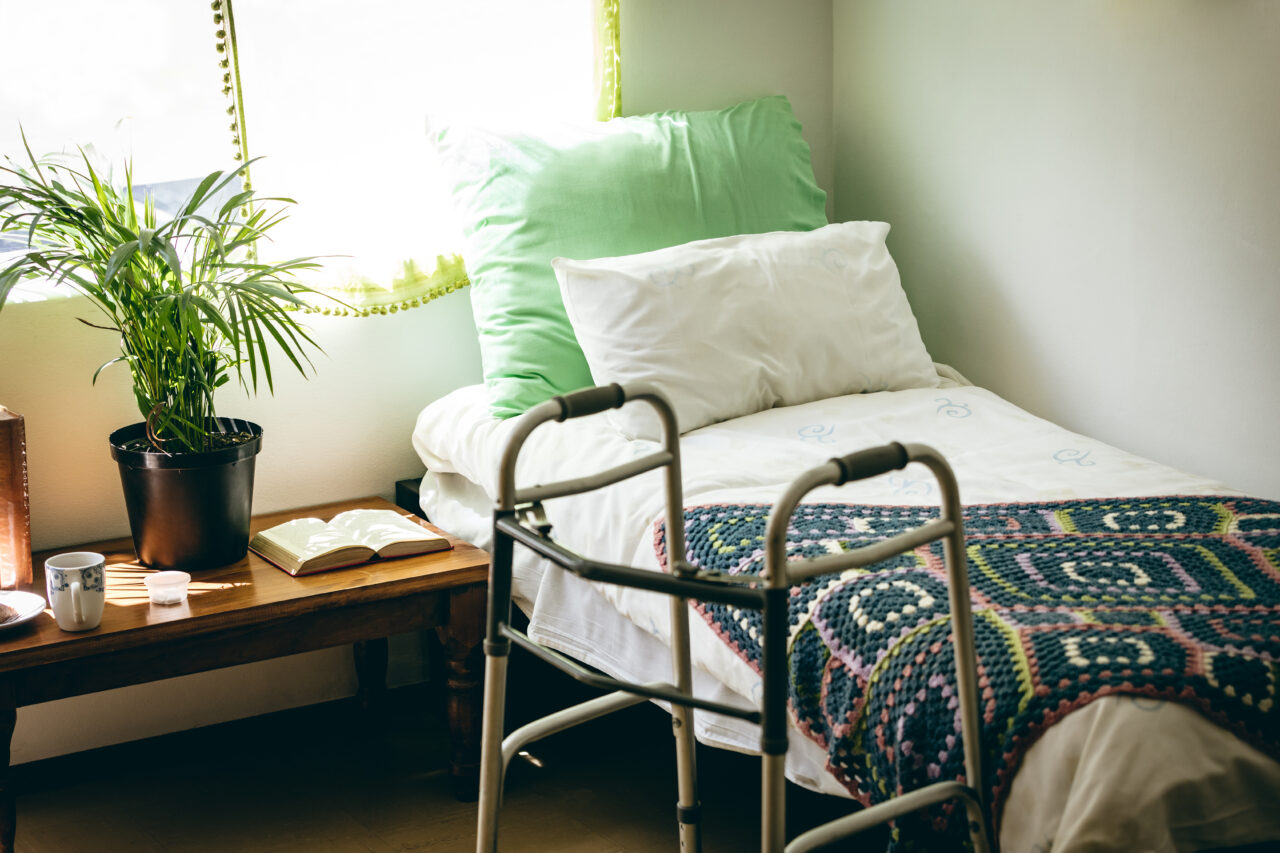 Empty bed and walker in bed room at retirement home